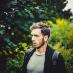A man stands outdoors surrounded by lush green foliage reflection—ideal for a counselling blog focused on emotional wellbeing.