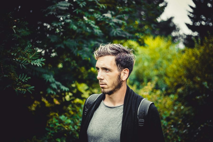 A-man-stands-outdoors-surrounded-by-lush-green-foliage-reflection—ideal-for-a-counselling-blog-focused-on-emotional-wellbeing